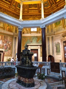 au centre les fonts baptismaux en basalte entour&eacute;s de 8 colonnes en porphyre rouge